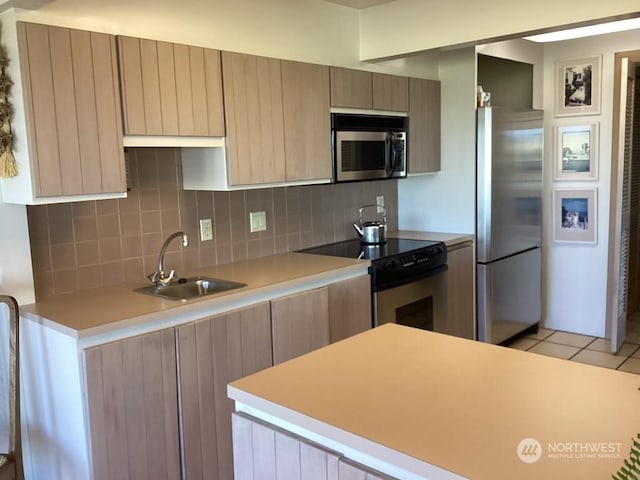 kitchen with backsplash, sink, light tile patterned floors, and stainless steel appliances