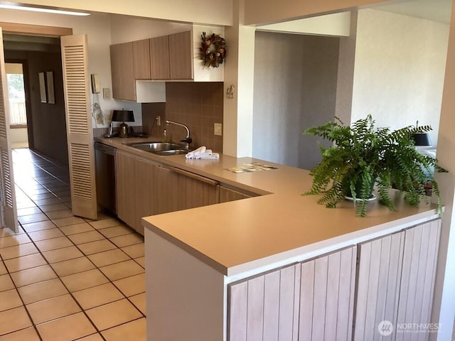 kitchen with sink, light tile patterned flooring, dishwasher, kitchen peninsula, and decorative backsplash