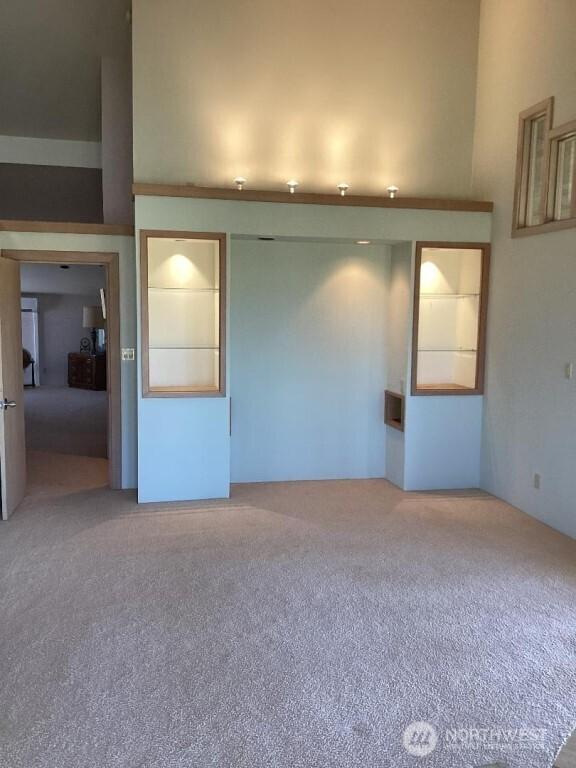 carpeted empty room with a high ceiling