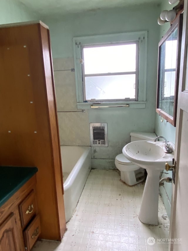 bathroom featuring toilet, heating unit, and a bathing tub