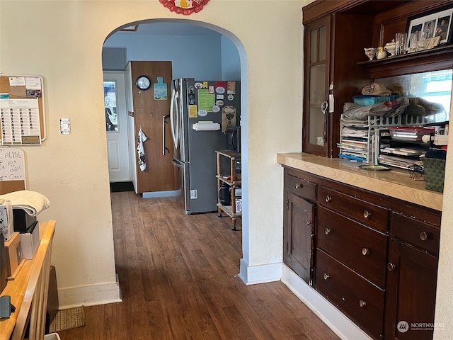 kitchen with stainless steel fridge, dark wood-type flooring, and dark brown cabinetry