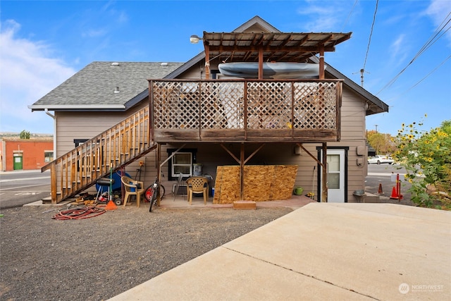 rear view of property featuring a wooden deck and a patio area