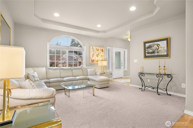 living room with light carpet, recessed lighting, a raised ceiling, and baseboards