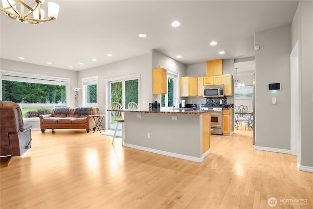 kitchen with open floor plan, stainless steel appliances, dark stone counters, and an inviting chandelier