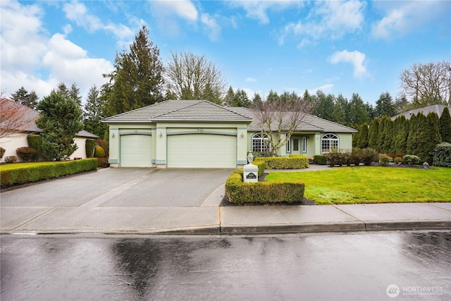 view of front of home featuring a garage, concrete driveway, a tiled roof, a front lawn, and stucco siding