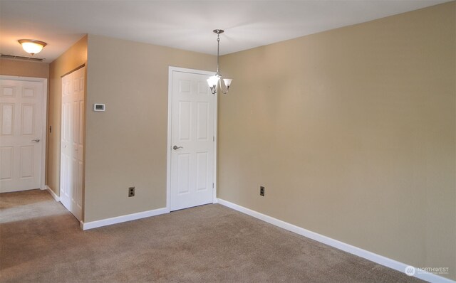 empty room with carpet flooring and a chandelier