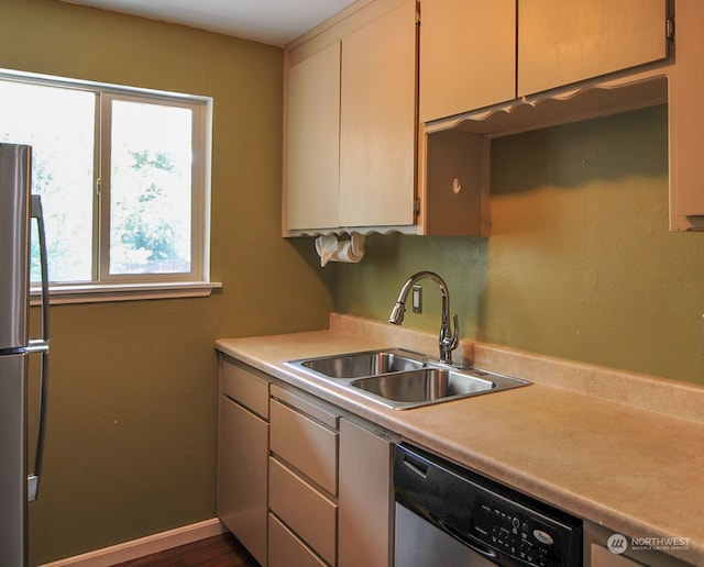 kitchen with appliances with stainless steel finishes, cream cabinetry, sink, and dark wood-type flooring