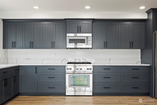 kitchen featuring gray cabinets, appliances with stainless steel finishes, light stone counters, and light hardwood / wood-style floors