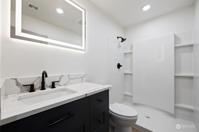 bathroom featuring vanity, toilet, and a shower