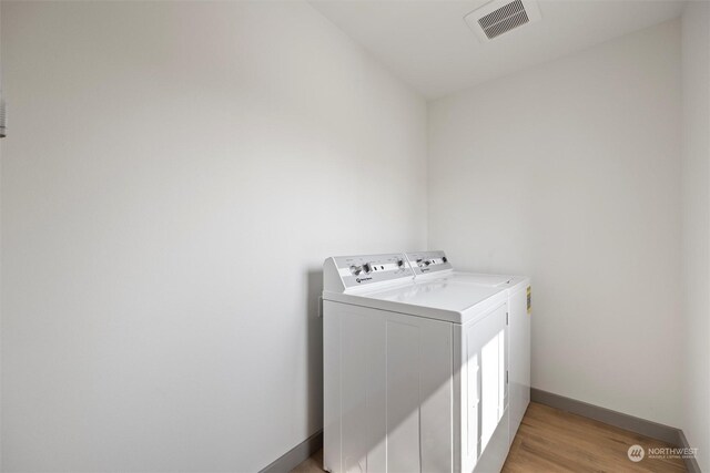 washroom featuring washing machine and dryer and light hardwood / wood-style floors