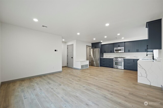 kitchen featuring light hardwood / wood-style flooring, sink, light stone countertops, and appliances with stainless steel finishes