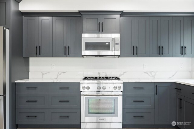 kitchen featuring gray cabinets, light stone counters, and stainless steel appliances