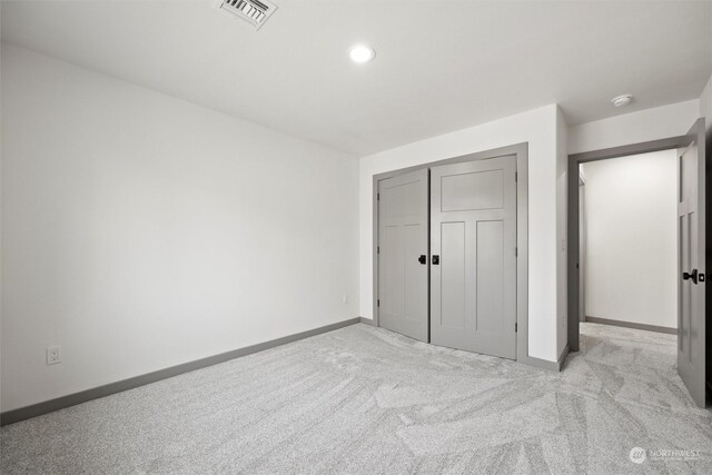 unfurnished bedroom featuring light carpet and a closet