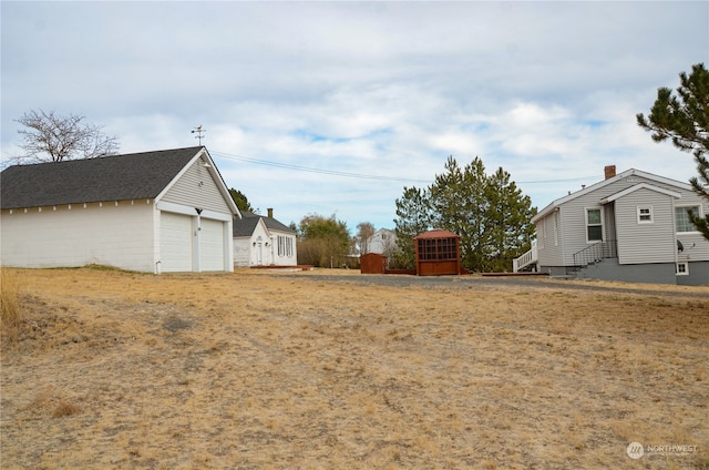 view of yard with a garage and an outbuilding