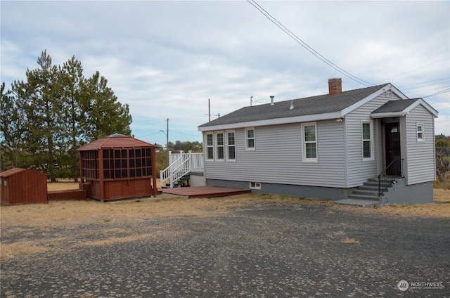 rear view of house with a storage shed and a deck