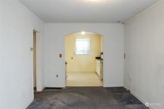 empty room featuring dark carpet and a textured ceiling