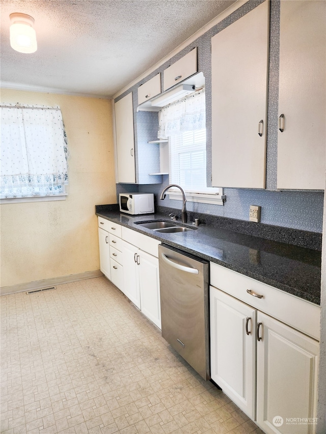 kitchen with stainless steel dishwasher, sink, white cabinets, and a textured ceiling