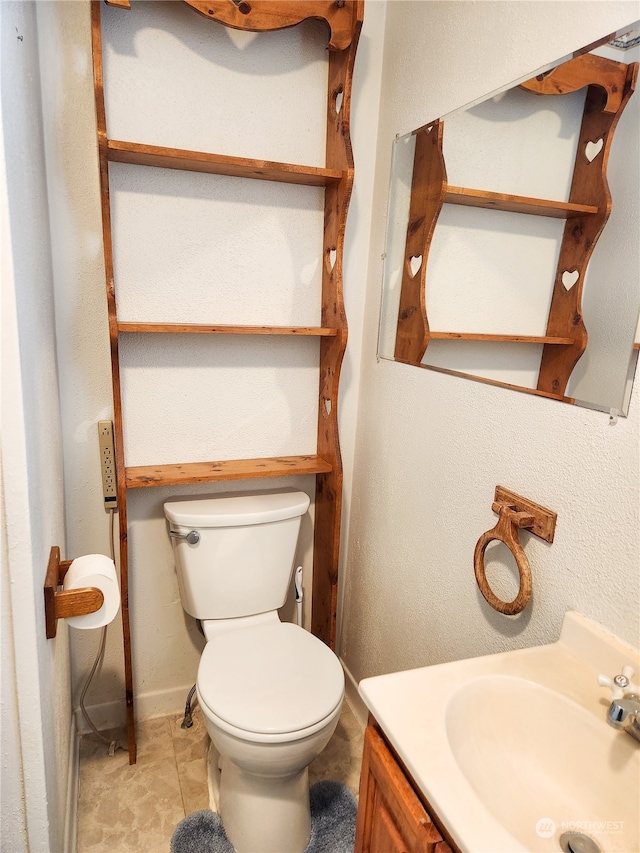 bathroom with toilet, vanity, and tile patterned flooring