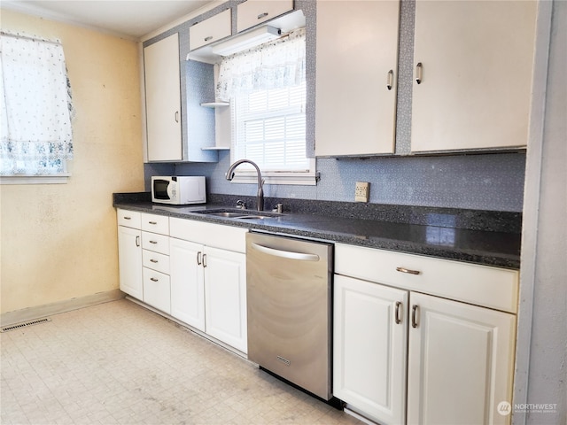 kitchen featuring dishwasher, white cabinets, sink, and backsplash