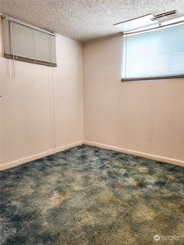 carpeted empty room with a textured ceiling