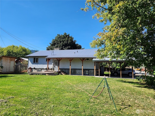 back of property with a storage shed, a deck, a lawn, and a carport