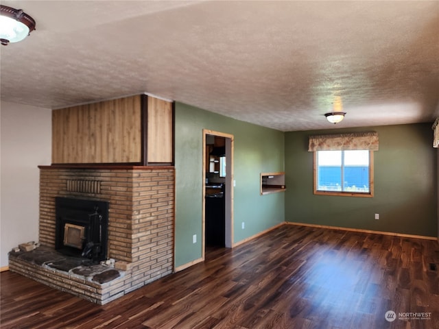 unfurnished living room featuring dark hardwood / wood-style flooring, a textured ceiling, and a brick fireplace