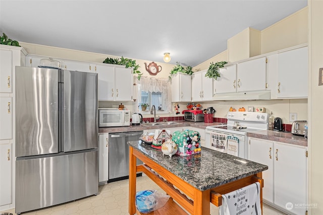 kitchen with stainless steel appliances, sink, white cabinets, and dark stone counters