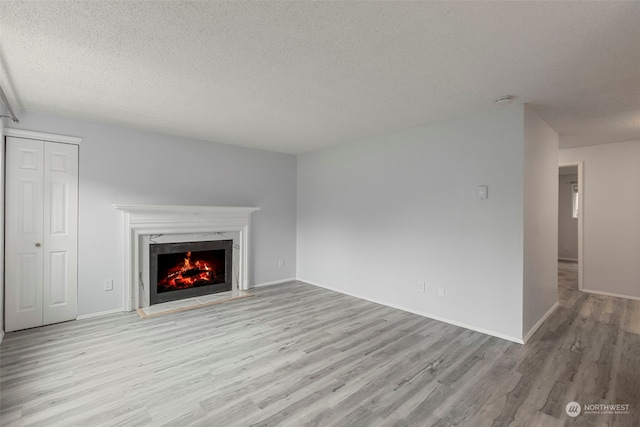 unfurnished living room featuring a fireplace, a textured ceiling, and light hardwood / wood-style flooring