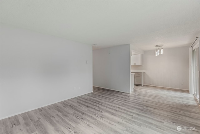 unfurnished living room featuring light hardwood / wood-style flooring and a textured ceiling