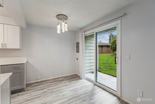 unfurnished dining area with light hardwood / wood-style floors and a textured ceiling