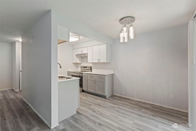 kitchen featuring pendant lighting, stainless steel range with electric cooktop, sink, light wood-type flooring, and a textured ceiling