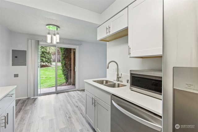 kitchen with appliances with stainless steel finishes, sink, pendant lighting, white cabinets, and electric panel