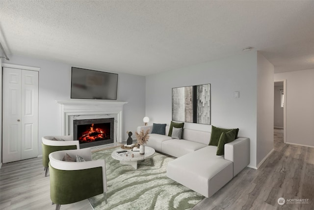 living room featuring a premium fireplace, light hardwood / wood-style flooring, and a textured ceiling