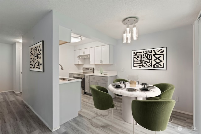 interior space featuring white cabinetry, sink, pendant lighting, a textured ceiling, and stainless steel electric range