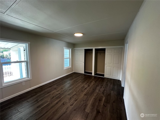 unfurnished bedroom with dark hardwood / wood-style flooring and two closets