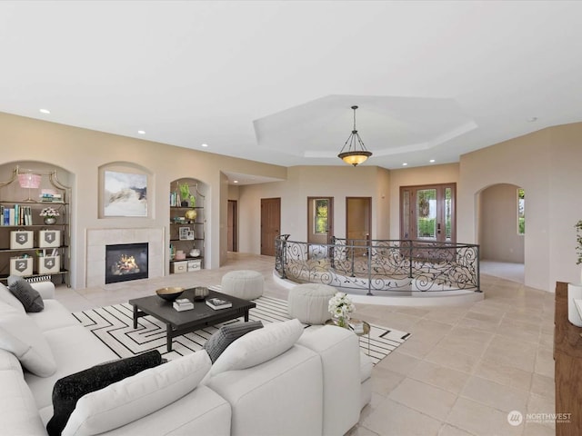 tiled living room featuring a fireplace and a tray ceiling