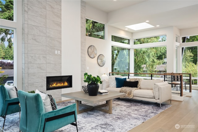 living room featuring a wealth of natural light, a tile fireplace, wood-type flooring, and a skylight