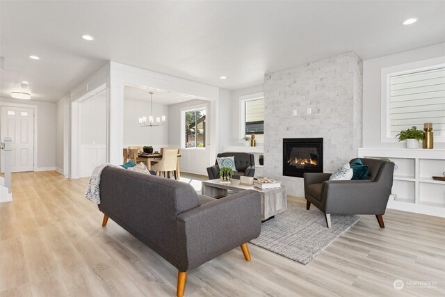 living room featuring light hardwood / wood-style flooring, a notable chandelier, and a fireplace