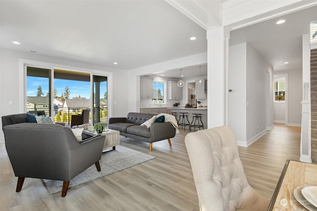 living room featuring recessed lighting, baseboards, light wood-style floors, and ornate columns