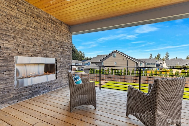 wooden terrace featuring fence, a residential view, and an outdoor stone fireplace