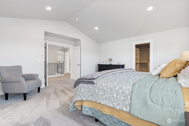 bedroom with vaulted ceiling, a spacious closet, light colored carpet, and a closet