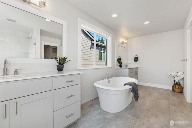 full bathroom featuring a freestanding tub, two vanities, a tile shower, and a sink