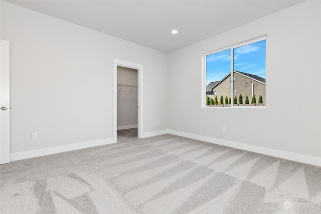 unfurnished bedroom with carpet, baseboards, recessed lighting, a spacious closet, and a closet