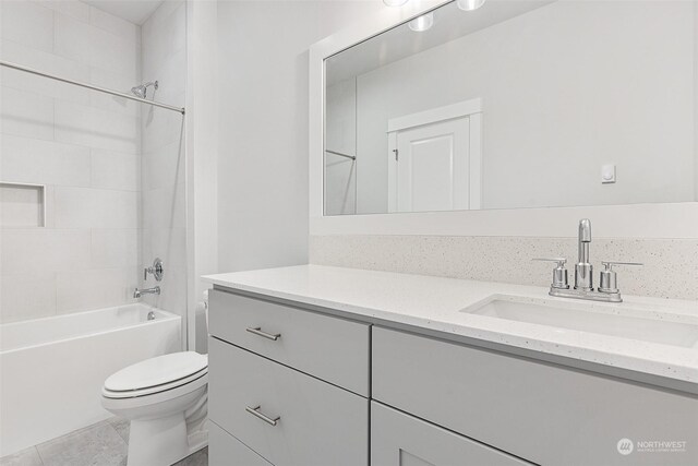 full bathroom with tiled shower / bath, vanity, toilet, and tile patterned floors