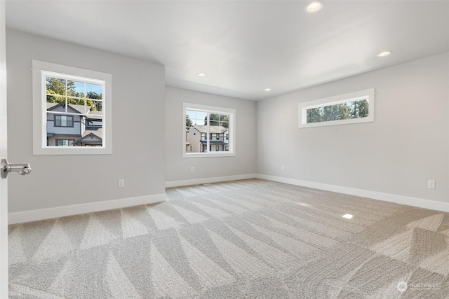 unfurnished room featuring light carpet, recessed lighting, a wealth of natural light, and baseboards