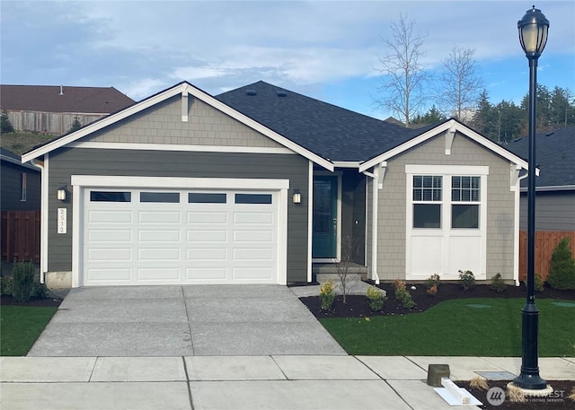 single story home featuring a shingled roof, concrete driveway, a front yard, fence, and a garage