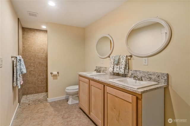 bathroom featuring a tile shower, vanity, tile patterned flooring, and toilet