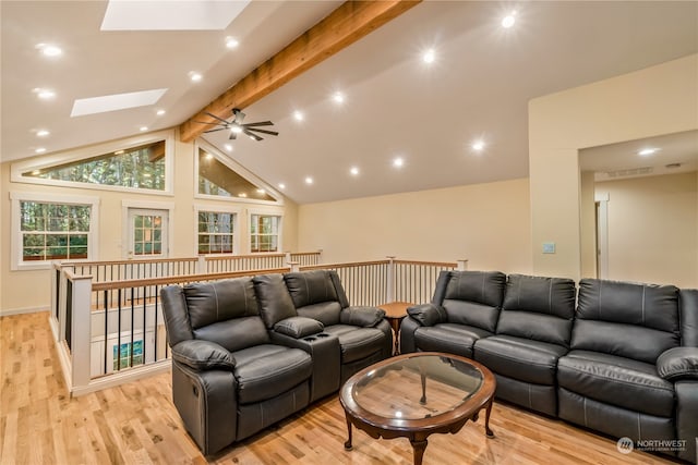 living room featuring ceiling fan, beamed ceiling, a skylight, light hardwood / wood-style flooring, and high vaulted ceiling