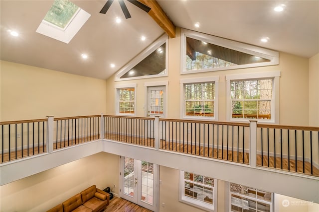 hall with high vaulted ceiling, beam ceiling, a skylight, and hardwood / wood-style floors