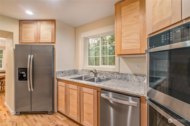 kitchen with light wood-type flooring, light stone counters, sink, stainless steel appliances, and light brown cabinets